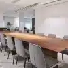 שולחן פינת אוכל דגם סיכה מעץ מלא עם קווים ישרים ונקיים, מוקף בכיסאות מרופדים באפור עם רגליים שחורות דקיקות. השולחן ממוקם בחלל מודרני ומואר עם תאורה עילית אלגנטית המשתלבת בעיצוב המינימליסטי.